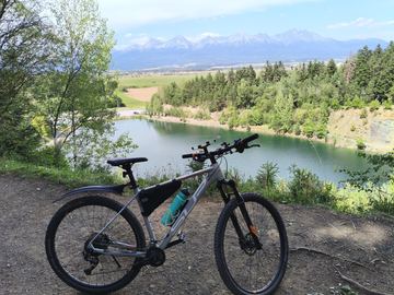 A mountain bike on a trail above a turquoise quarry lake, the Tatry mountains behind