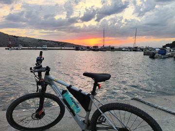 A bike on a harbour pier at sunset, boats on the water